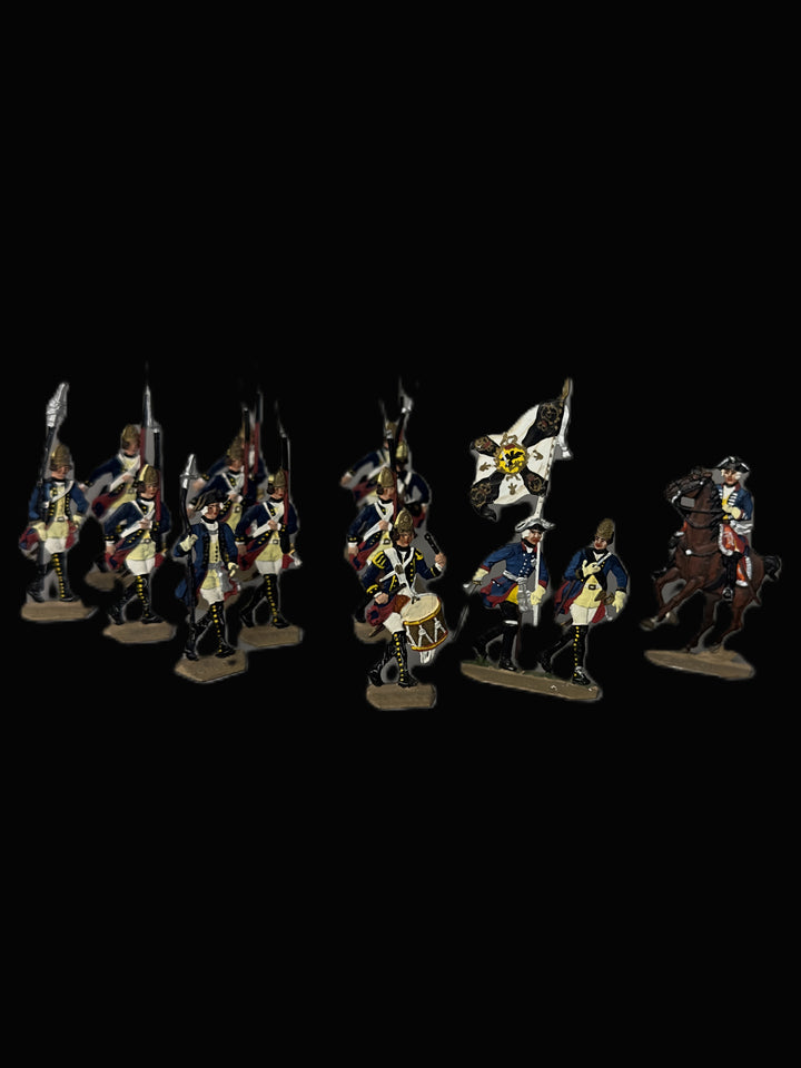 A set of painted historical military miniature figurines, including soldiers with rifles, a flag bearer, and a mounted soldier on a horse, displayed against a solid black background.
