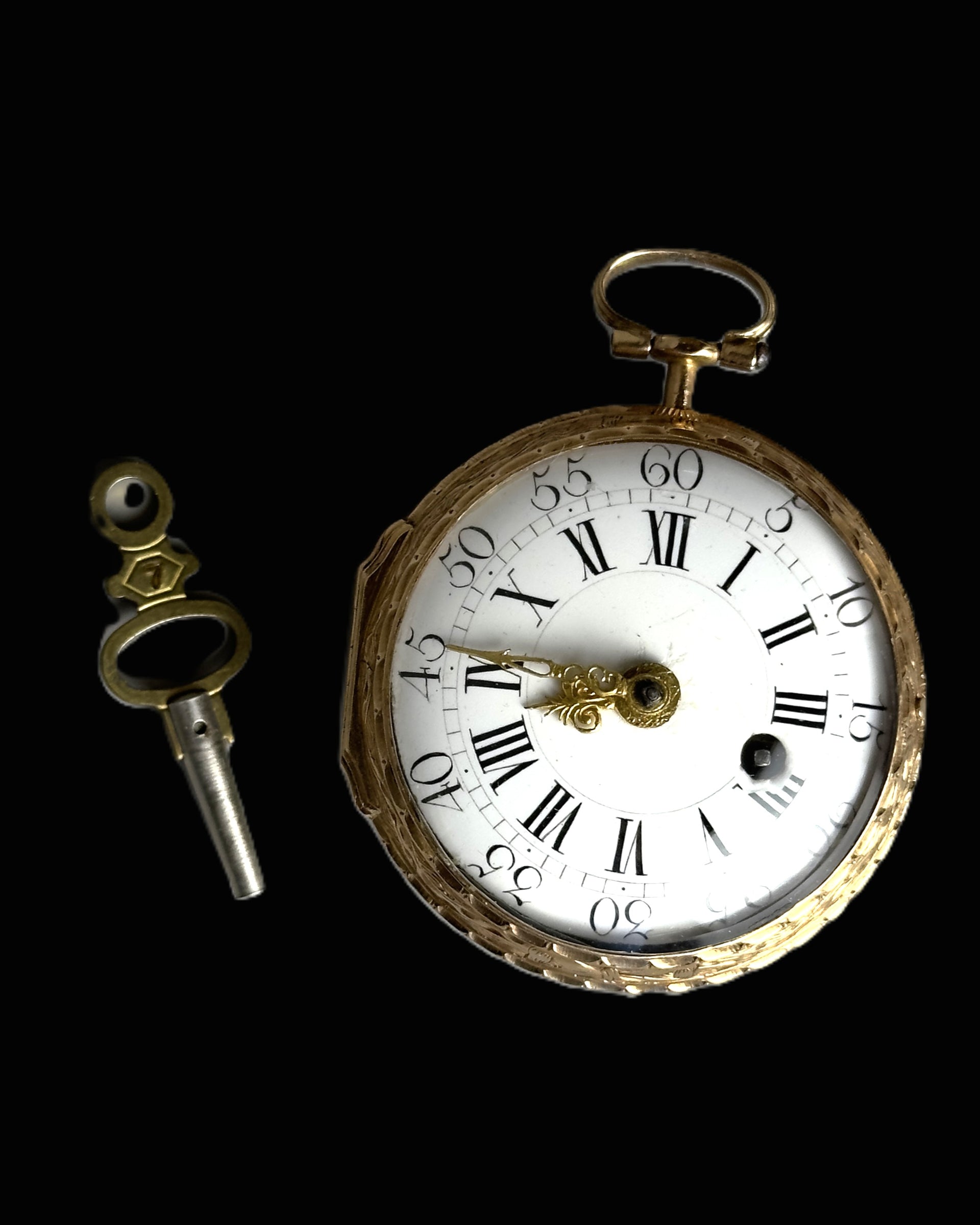 A vintage gold-toned pocket watch with a white dial and black Roman numerals, shown alongside a matching key on a solid black background.