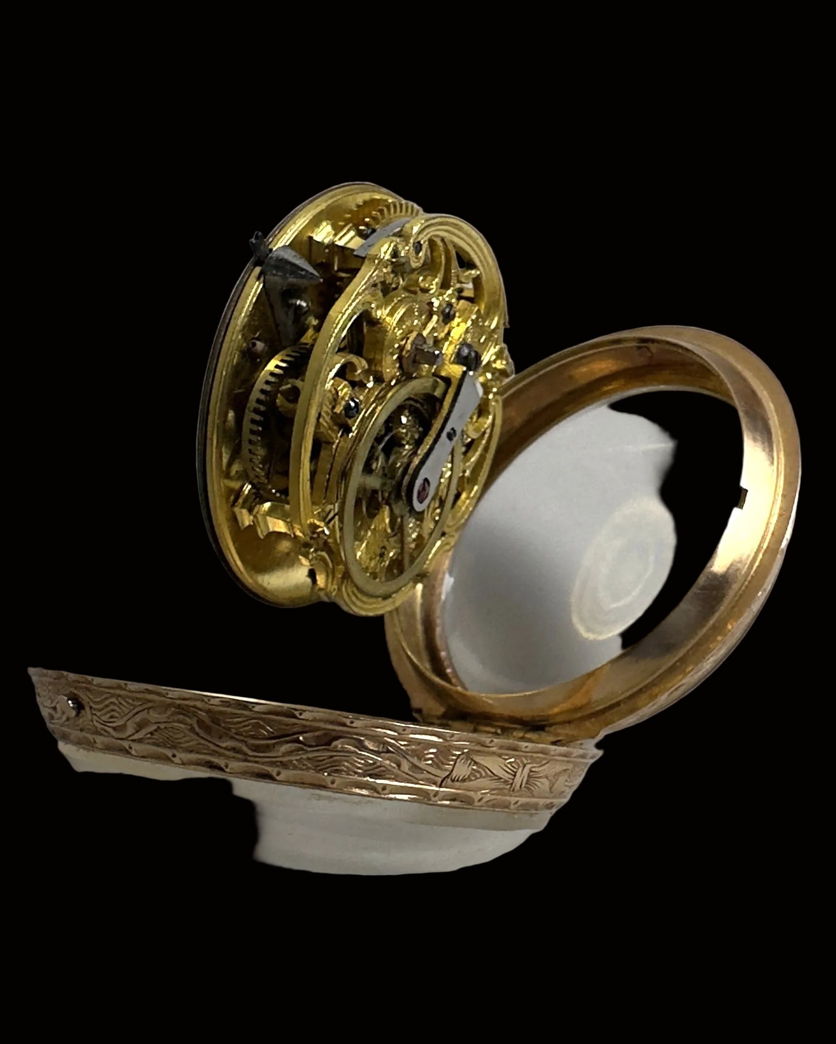 An antique gold pocket watch mechanism with ornate gears and a polished gold-toned case, shown open against a neutral light gray background.