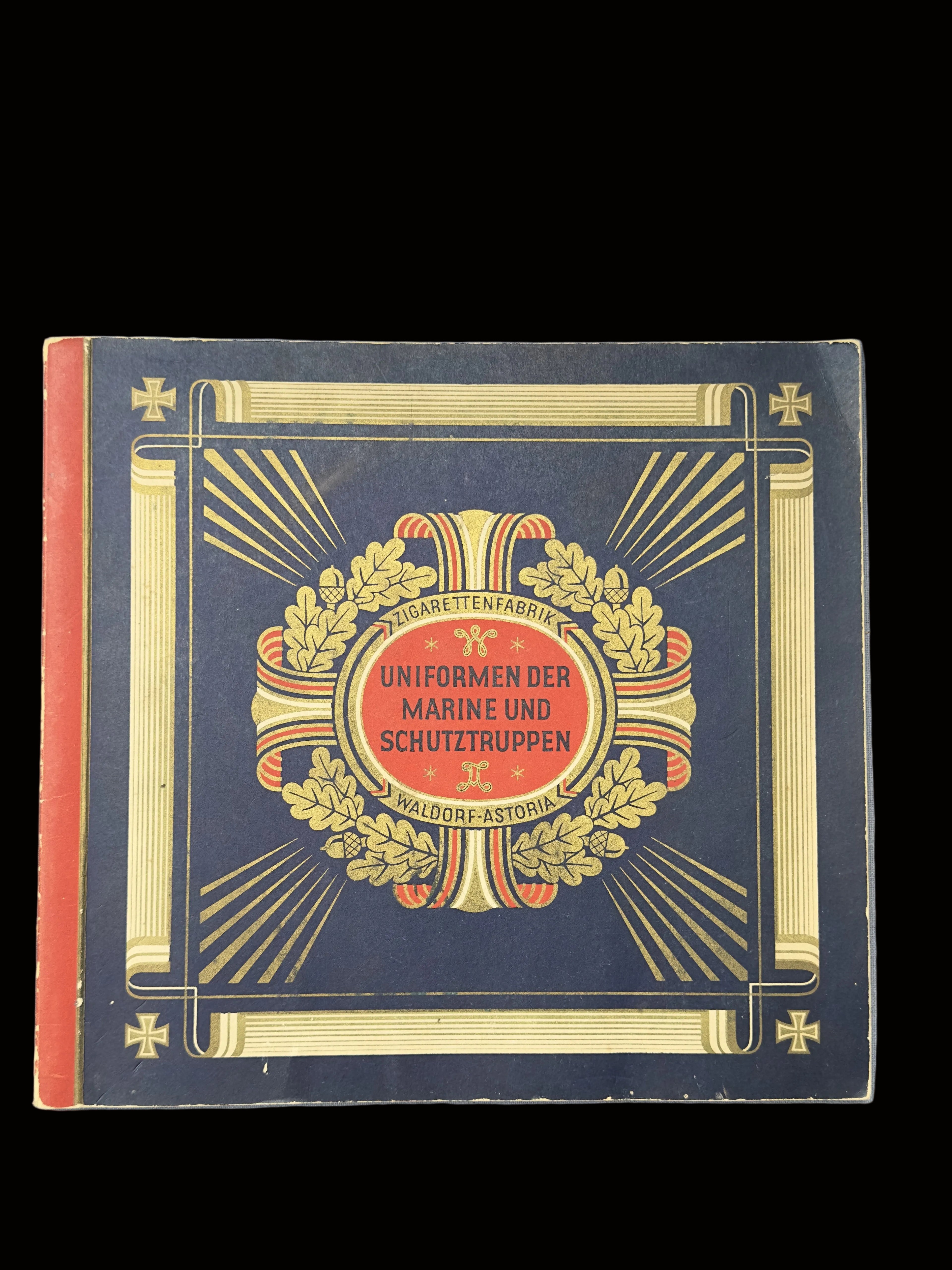 A vintage book or booklet titled 'Uniformen der Marine und Schutztruppen' by Hugo Feuchtwand, featuring a dark navy cover with gold decorative borders, a central red oval, and a laurel wreath illustration.