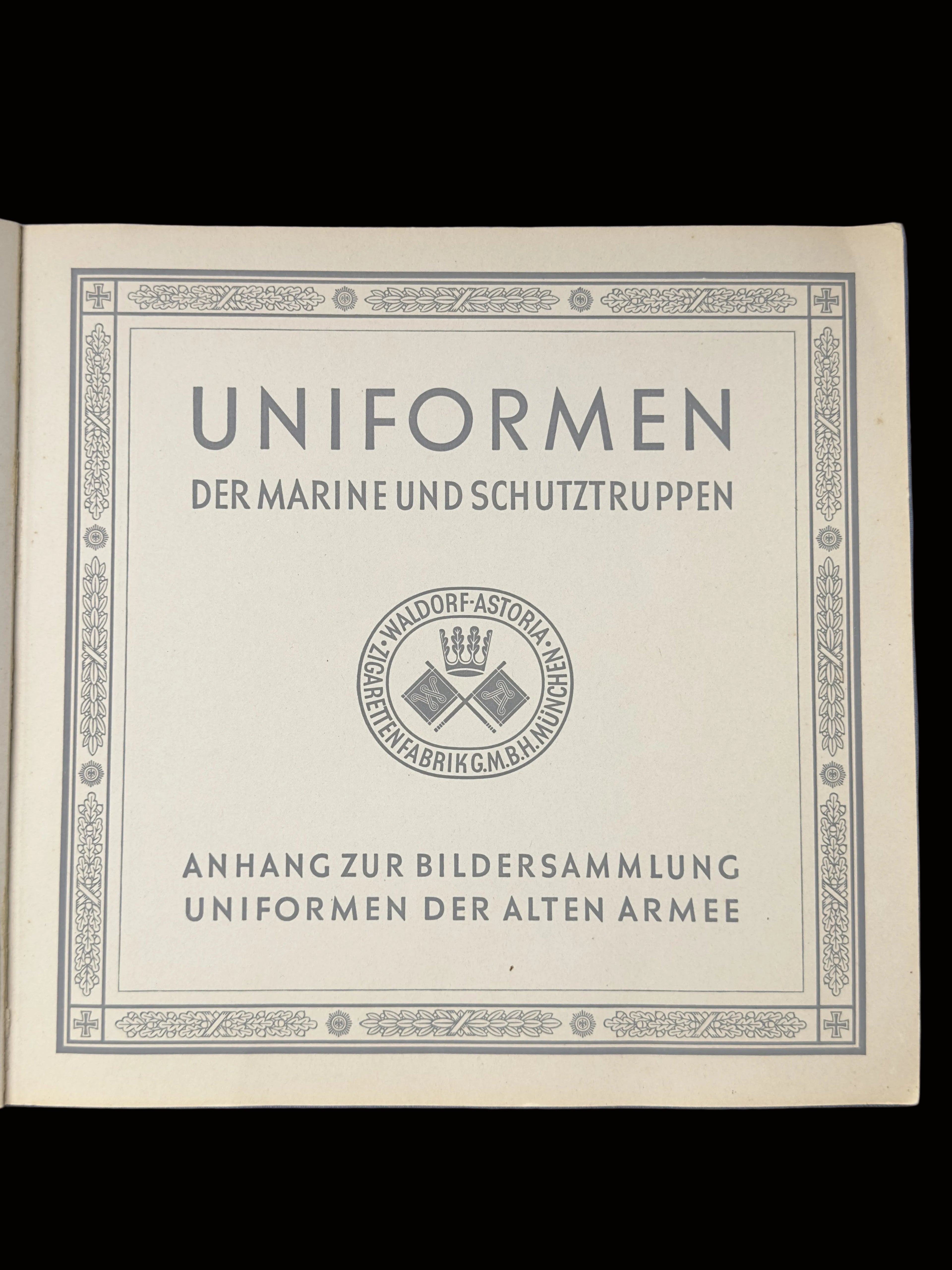 A vintage German military uniform booklet titled 'UNIFORMEN DER MARINE UND SCHUTZTRUPPEN' on aged beige paper, photographed flat against a blue background.