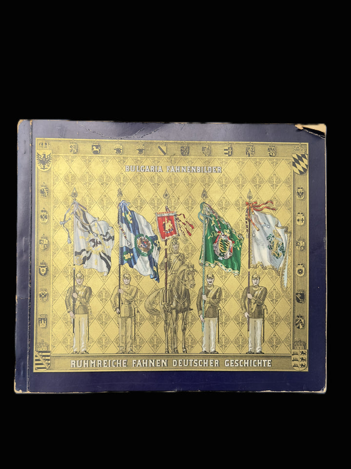 A vintage German book titled 'Ruhmreiche Fahren Deutscher Geschichte' featuring a gold and navy blue cover with illustrations of historical flags and figures, photographed against a solid black background.