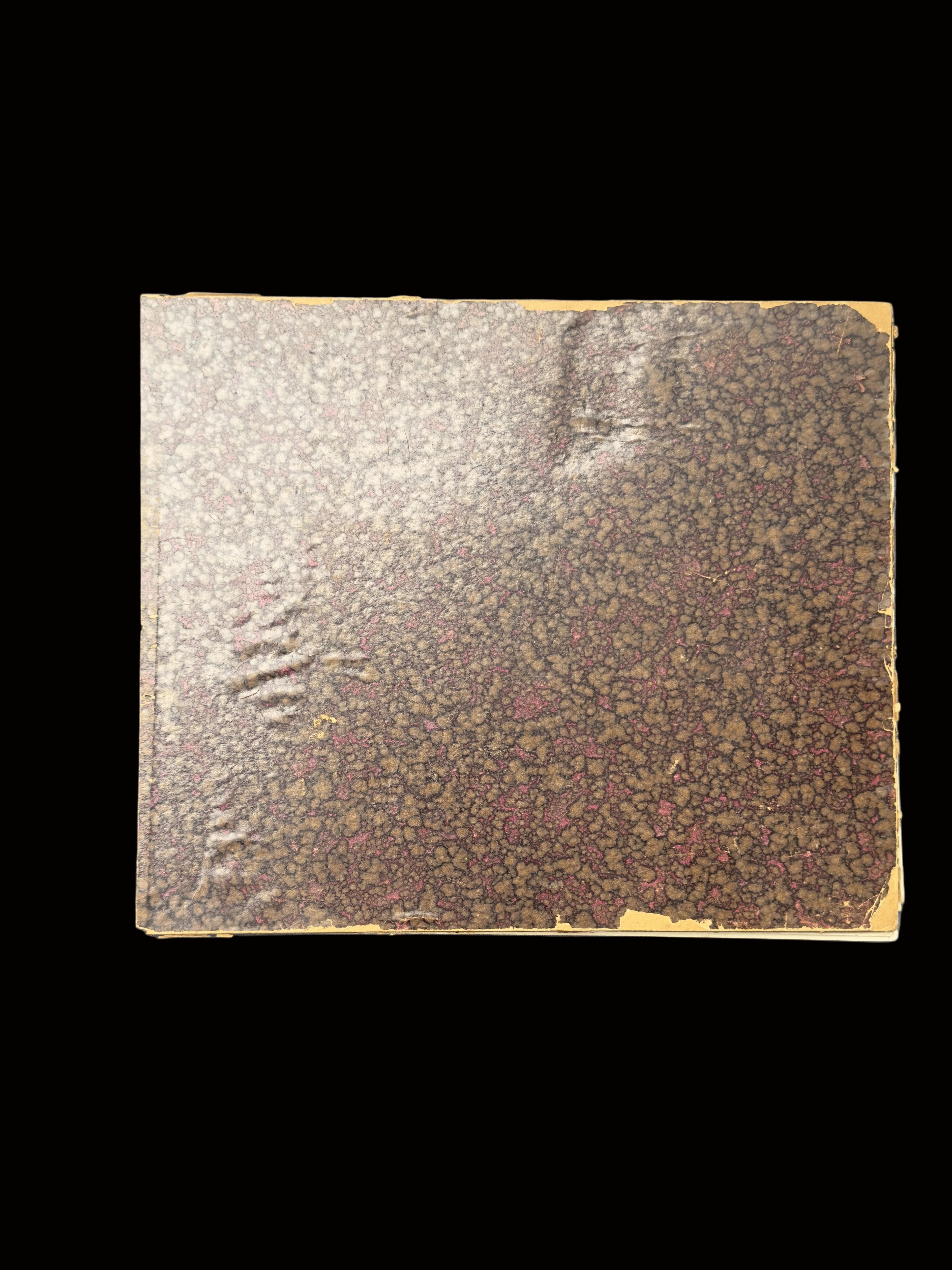 An antique hardcover book with a marbled brown and gold paper cover and a dark gray cloth spine, photographed on a gray surface.