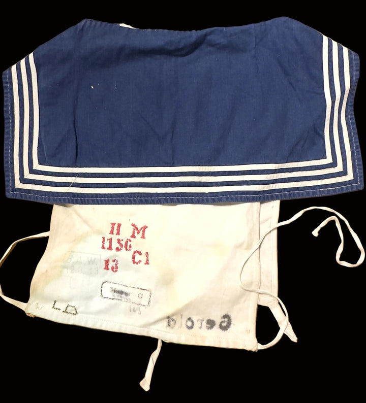 A vintage navy blue sailor-style collar with white stripes laid flat on a tan cardboard background, positioned above a white canvas drawstring pouch with red and black printed markings.