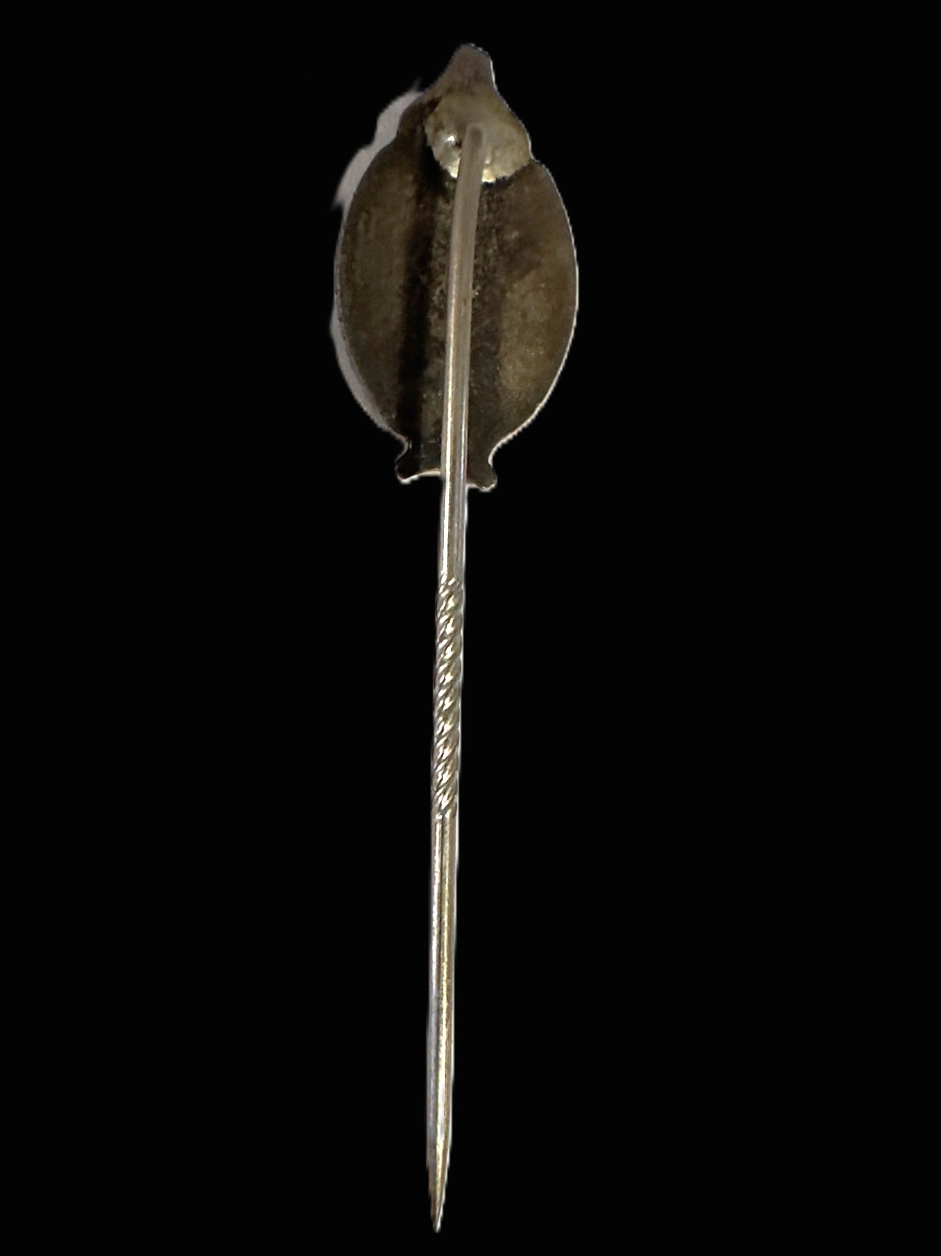 A vintage silver-toned pin with a stylized leaf-shaped back and a long pointed stem, shown against a solid black background.