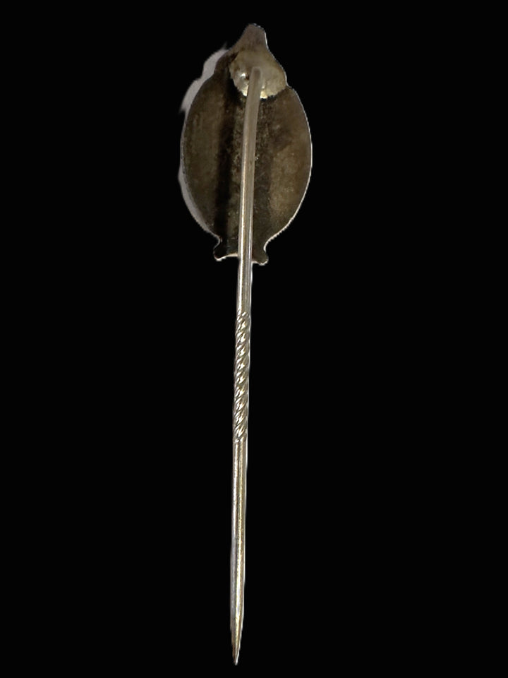 A vintage silver-toned pin with a stylized leaf-shaped back and a long pointed stem, shown against a solid black background.